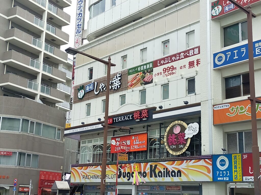 桃菜をはじめ複数の飲食店の看板が並ぶ、都市部の商業ビル外観の写真