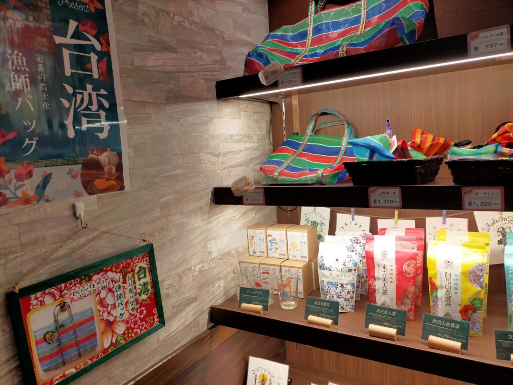 木製棚に中国茶やお菓子のパッケージが並び、その下にメニューが置かれた桃菜店内の装飾コーナーの写真