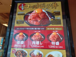 ローストビーフ丼やからあげ丼など数種類の肉丼の写真と価格が載った、肉丼の星のカラフルなメニュー看板のクローズアップ写真