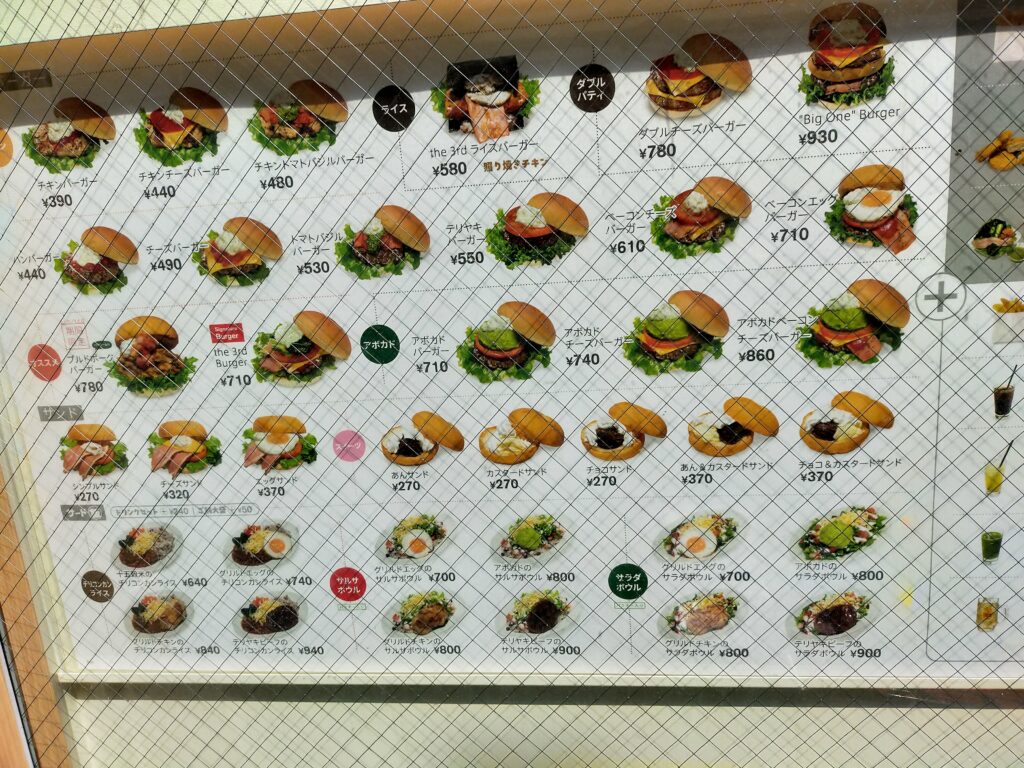「各種ハンバーガーとサイド、ドリンクの写真と価格が並ぶthe 3rd Burgerの店内メニューボード」