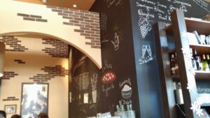 「レンガアーチと黒板アートがあるサルバトーレ店内入口。壁にはピザやワインのイラストとメニューが描かれている」