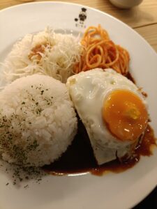「白い丸皿に、ご飯2つとデミグラスソースのハンバーグ、目玉焼き、少量のナポリタンとサラダが盛られた喫茶店ピノキオの洋食プレート」