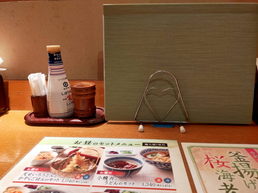 「銀座木屋のテーブルに七味やしょうゆ、仕切りパネルとランチメニューが並べられている様子」