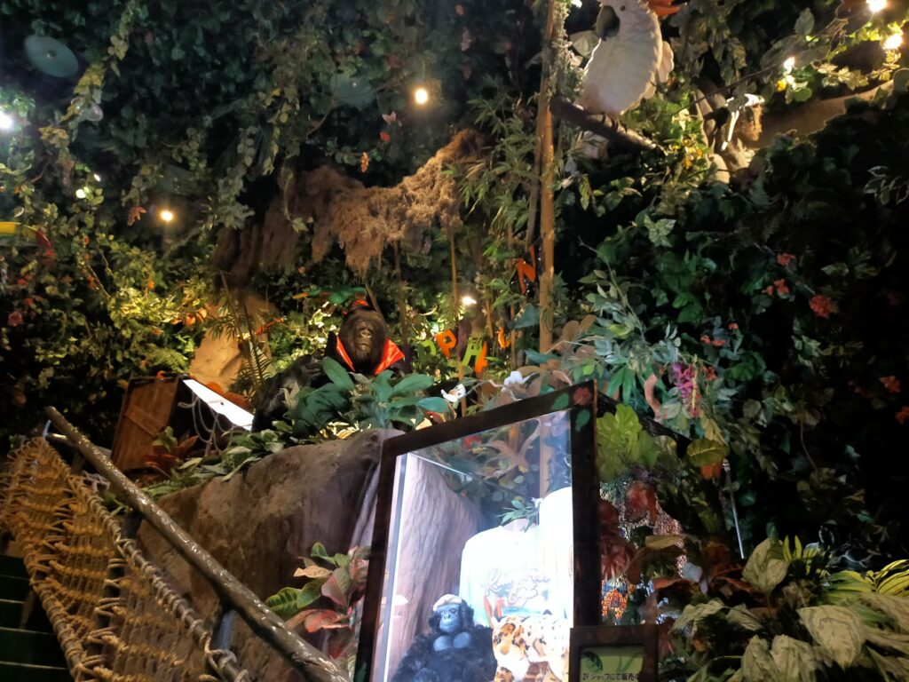 「レインフォレストカフェ東京の店内で、観葉植物に囲まれた大きな水槽とジャングル風の装飾が並ぶ様子」