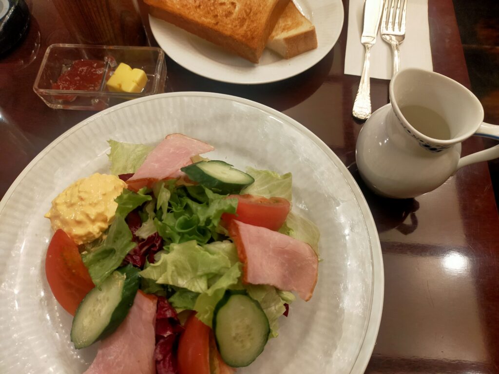 「ハムと野菜が盛られたサラダプレートと、奥にトーストとコーヒーカップが見える椿屋珈琲のモーニングセット」