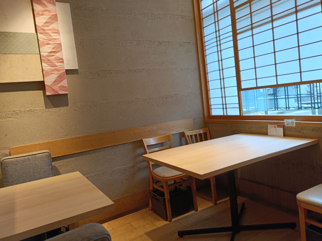 「木製テーブルとベンチシートが向かい合って並ぶ、はーべすと店内のテーブル席エリア」