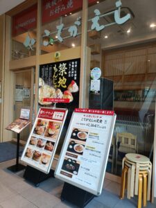 「ガラス張りの入口前にランチメニュー看板が並ぶ、こてがえし有楽町イトシア店の外観」