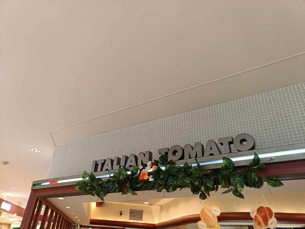 イタリアントマト店内のロゴサインとグリーン装飾が見える内装写真