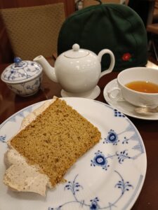 「椿屋カフェで提供される、紅茶のポットとカップ、ふわふわシフォンケーキがのった皿が並ぶティーセットのアップ」