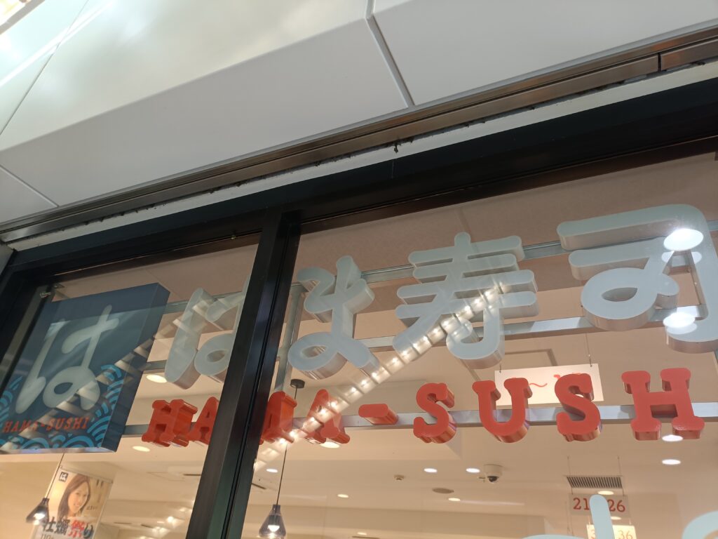 はま寿司の店舗入口付近のガラス面にあるロゴサイン。店名が大きく見える。