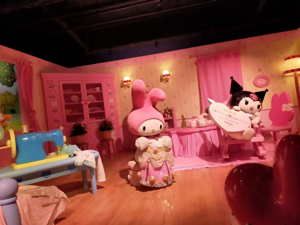 「ピンク色のステージにマイメロディなどサンリオキャラクターの等身大フィギュアが並んでいる館内フォトスポット」