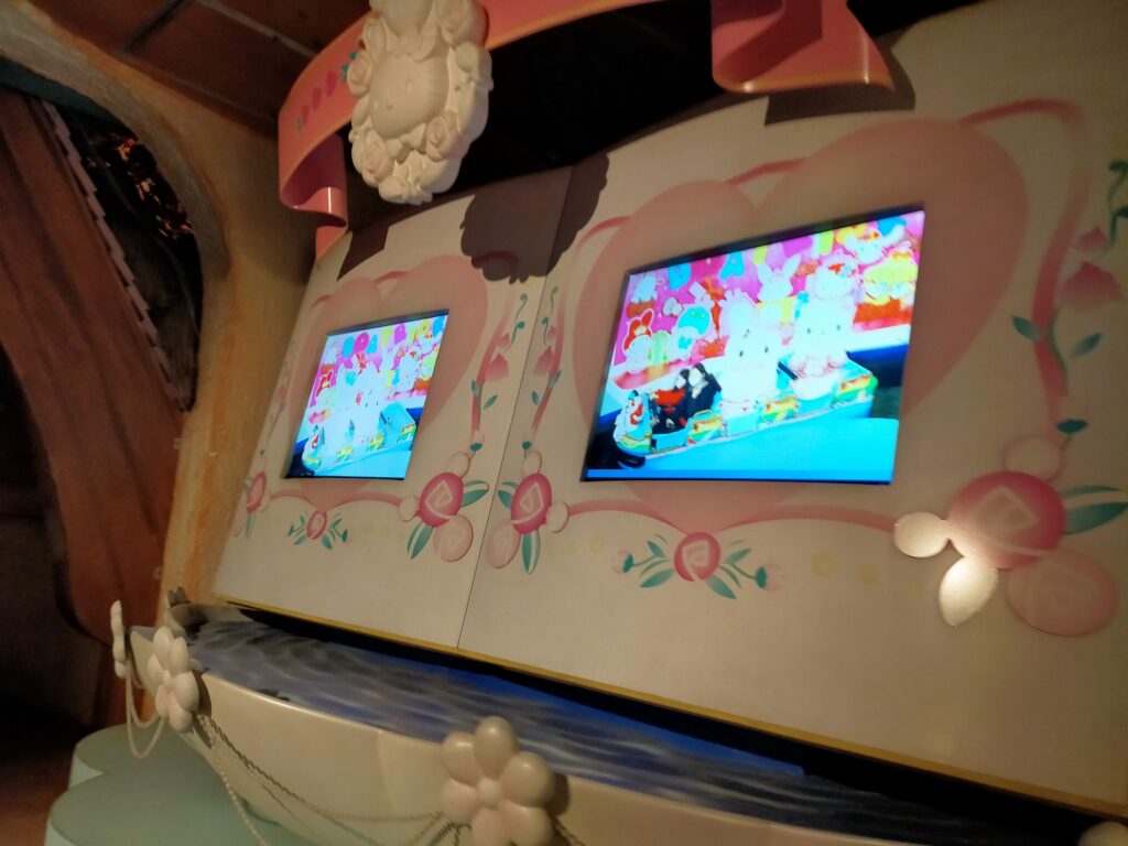 「サンリオキャラクターの装飾が描かれた壁に小型モニターが2台並び、アニメ映像が流れているキッズ向けコーナー」