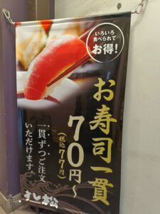すし松の店頭ポスター。寿司の写真と価格・キャンペーン告知が掲載されている。