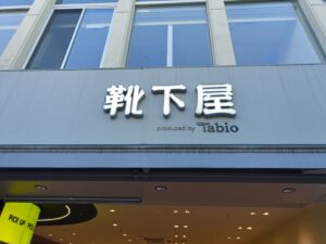 「ビルの1階に『靴下屋』の大きな文字とTabioロゴが付いた看板が見える店舗外観」