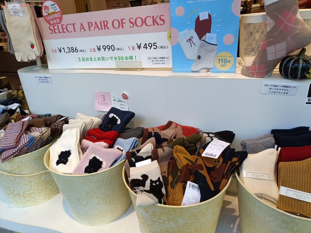 「バスケットにカラフルな靴下がたくさん入れられ、『3足○○円』と書かれたポップが付いている店頭ディスプレイ」