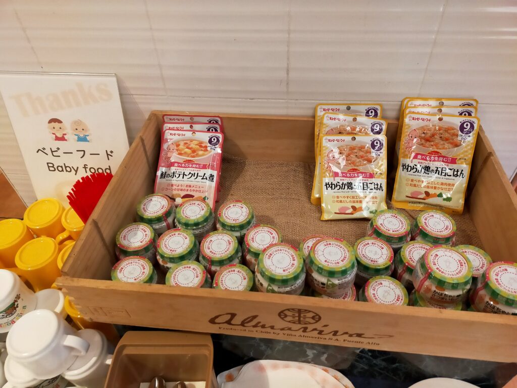 「木製トレーの上にヨーグルトの小さなカップや紙パックジュースが並んだホテルビュッフェの一角」