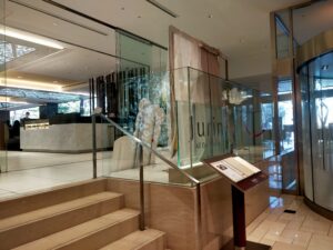 「京王プラザホテル新宿ロビーから続く階段と、ガラス越しに『Glass Court』のロゴが見えるレストラン入口」