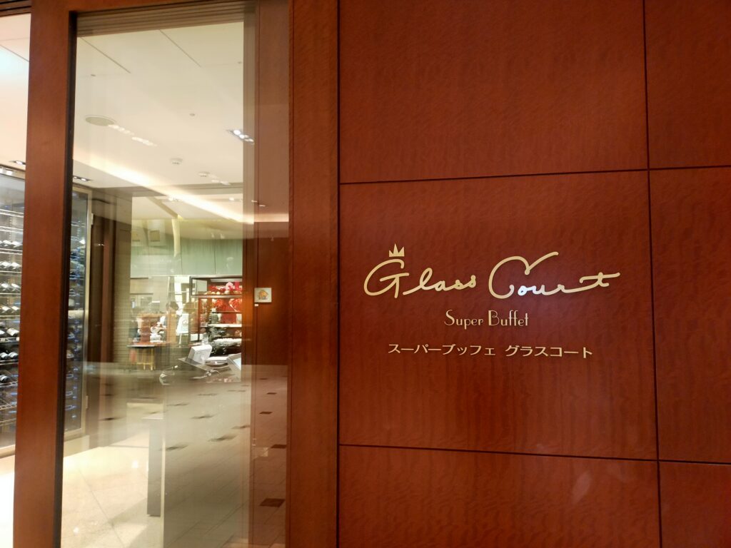 「木製の壁面に英字で『Glass Court Super Buffet Restaurant』と書かれた京王プラザホテル新宿レストランのロゴプレート」