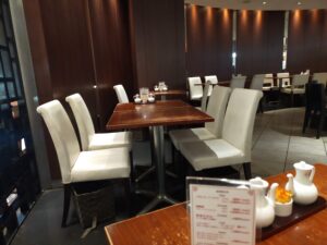 「暗めの木目の壁と白い椅子、木製テーブルが並ぶ香港蒸籠の店内テーブル席エリア」