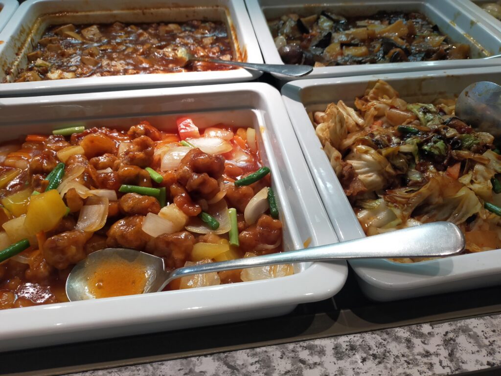 「酢豚や野菜炒めなど複数の中華料理がステンレス容器に入れられた香港蒸籠のホットビュッフェコーナー」