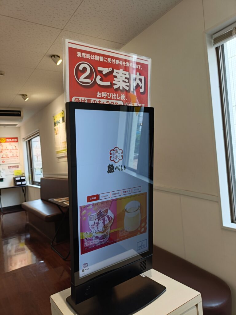 魚べい店内のデジタル案内表示。来店受付や呼び出しに使う画面が設置されている。