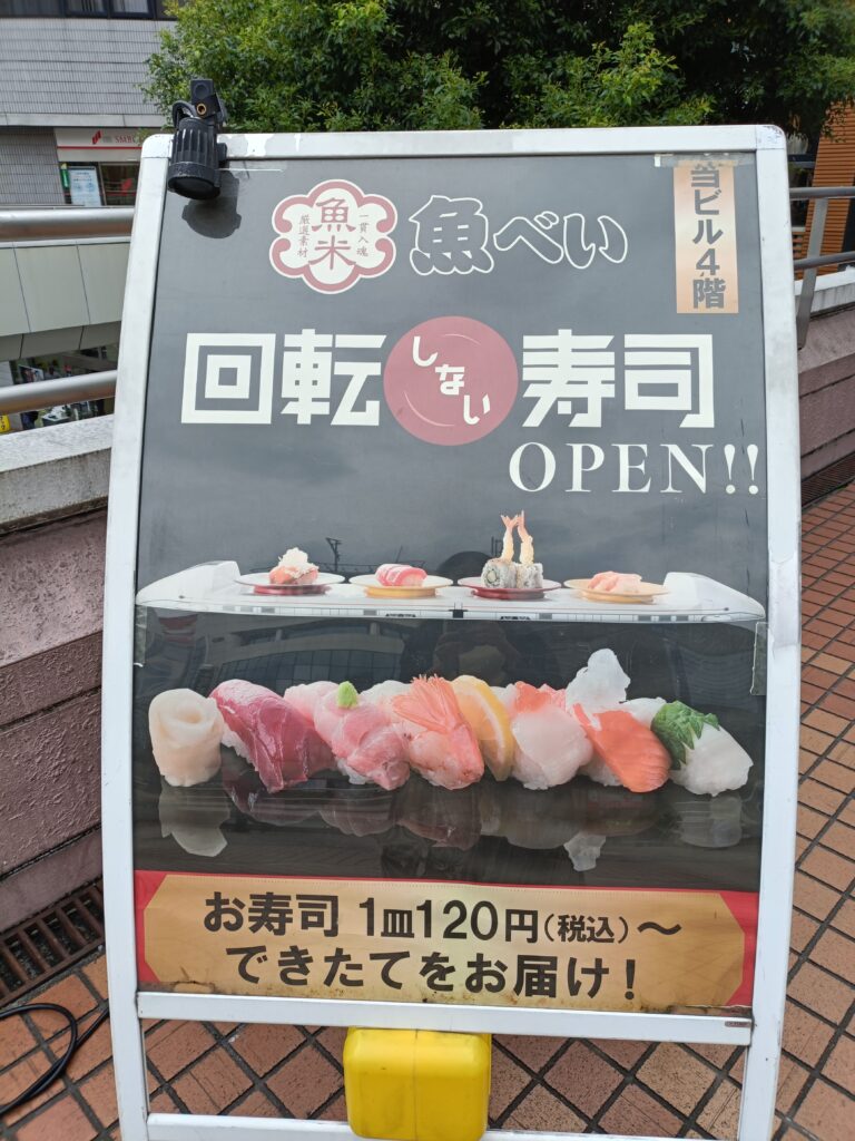 魚べいの店頭ポスター。回転寿司の案内文と寿司の盛り合わせ写真が掲載されている。