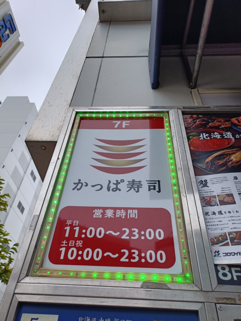 かっぱ寿司の店舗前にある縦長の案内看板。店名と営業時間が見える。