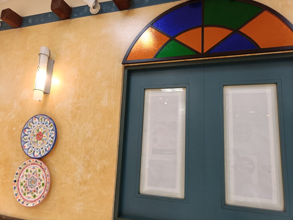 イタリアンダイニングDONAの入口ドアとステンドグラス風装飾がある外観